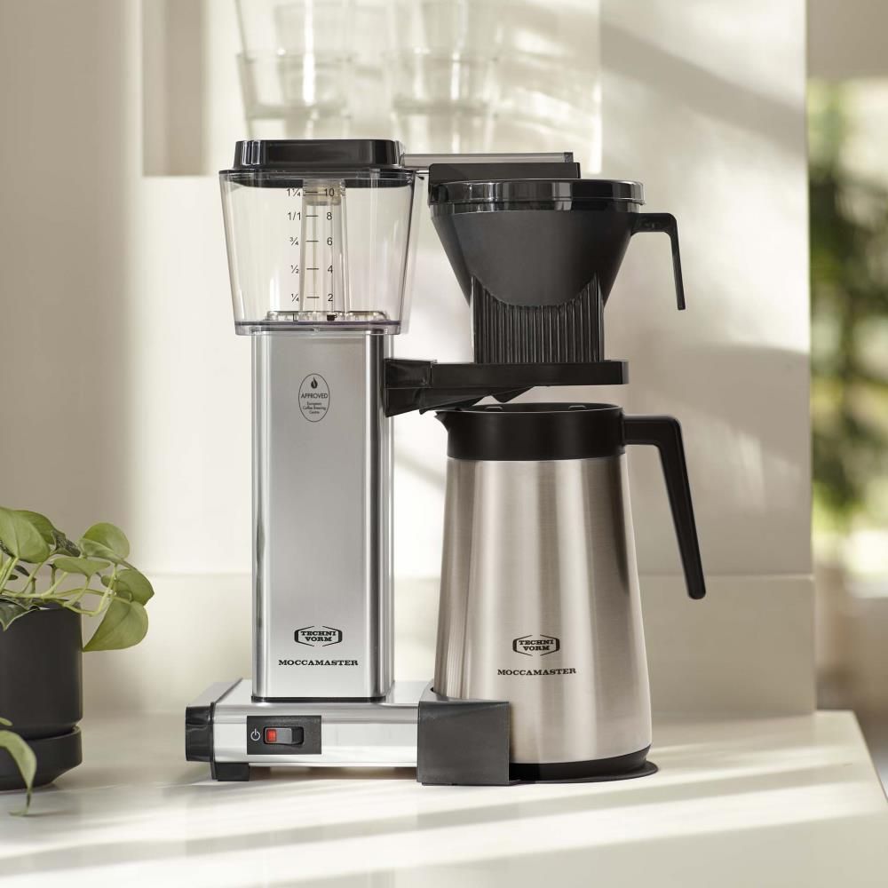 Moccamaster KBGT en aluminium poli posée sur un comptoir de cuisine moderne avec verseuse isotherme en inox